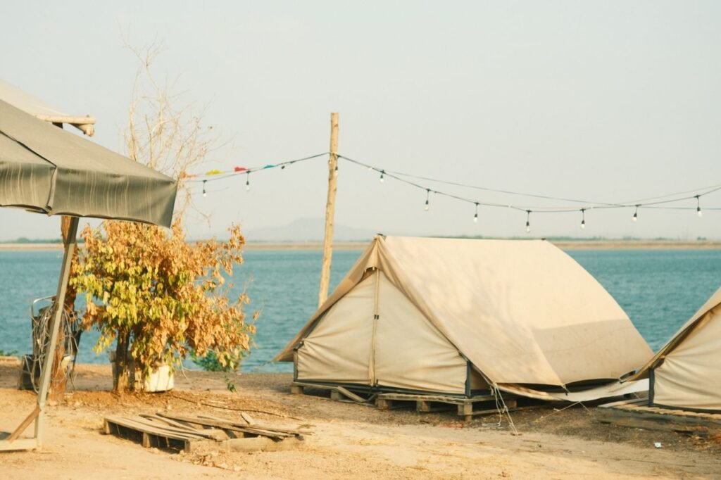 Serene camping setup by the river with tents under string lights.